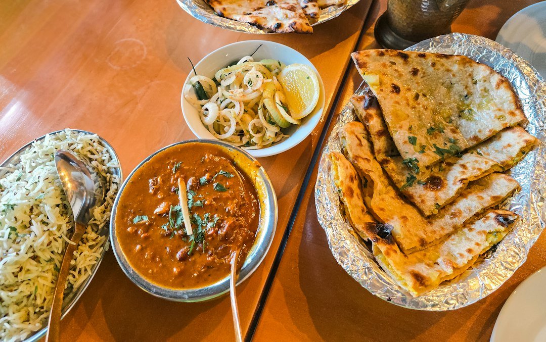 Indian restaurant meal with curry, jeera rice, flatbreads and onion salad