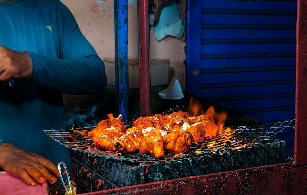 Chicken being grilled over open flames on a charcoal grill